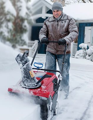 man using snow blower in storm 